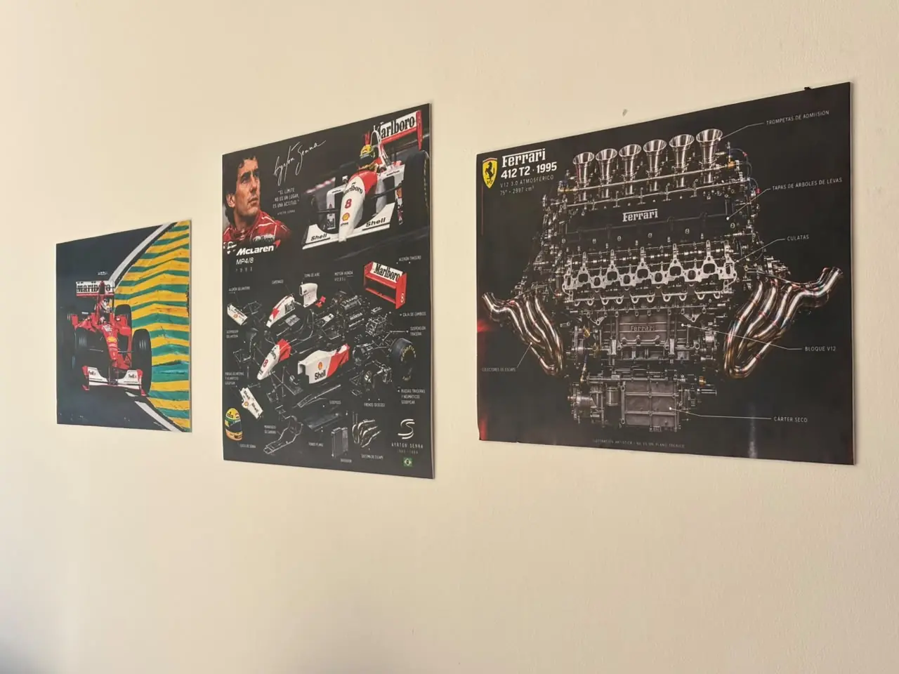 Cuadros de Fórmula 1 en la pared: Ferrari, el McLaren de Senna y un motor V12